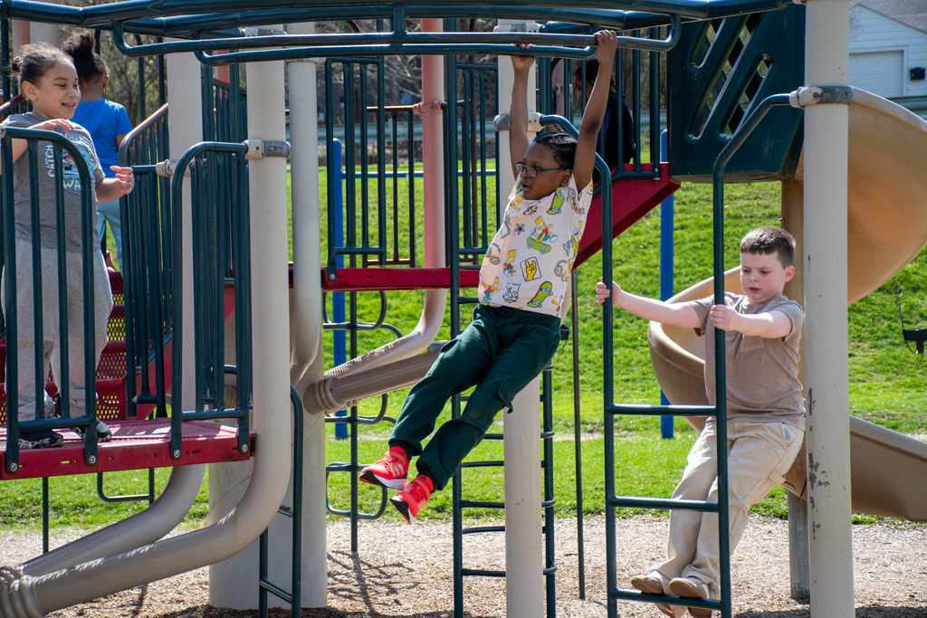 student climbs on monkey bars