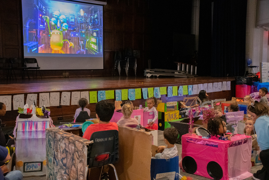 students watch movie in cardboard cars