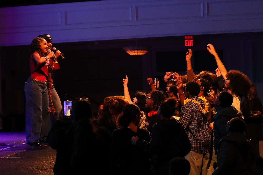 modern band students perform on stage with other students cheering them on in front