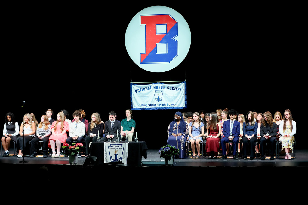 national honor society inductees sit on stage at helen foley theatre during induction ceremony