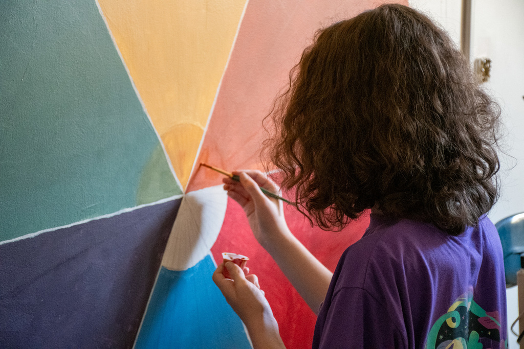 student paints on wall in classroom