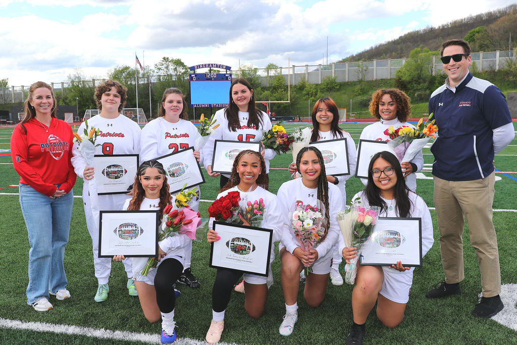 seniors from flag football team pose for photo with their coaches holding flowers