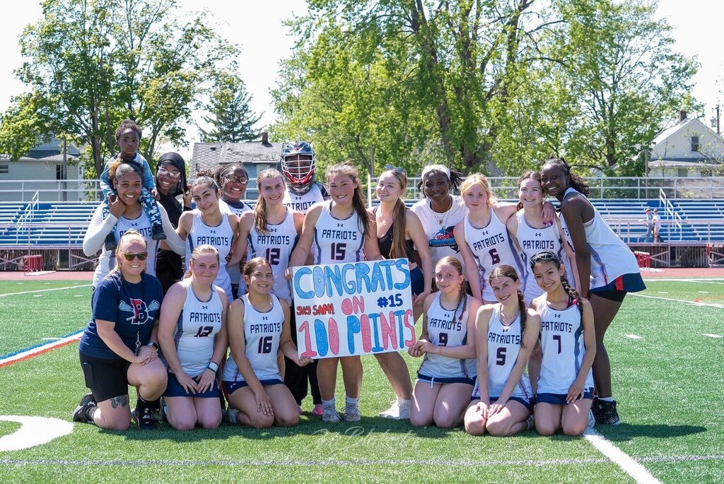 sam dalmolen holds sign congratulating her on 100 career points with teammates