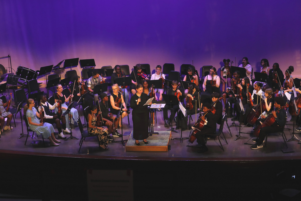 east middle orchestra students sit on stage