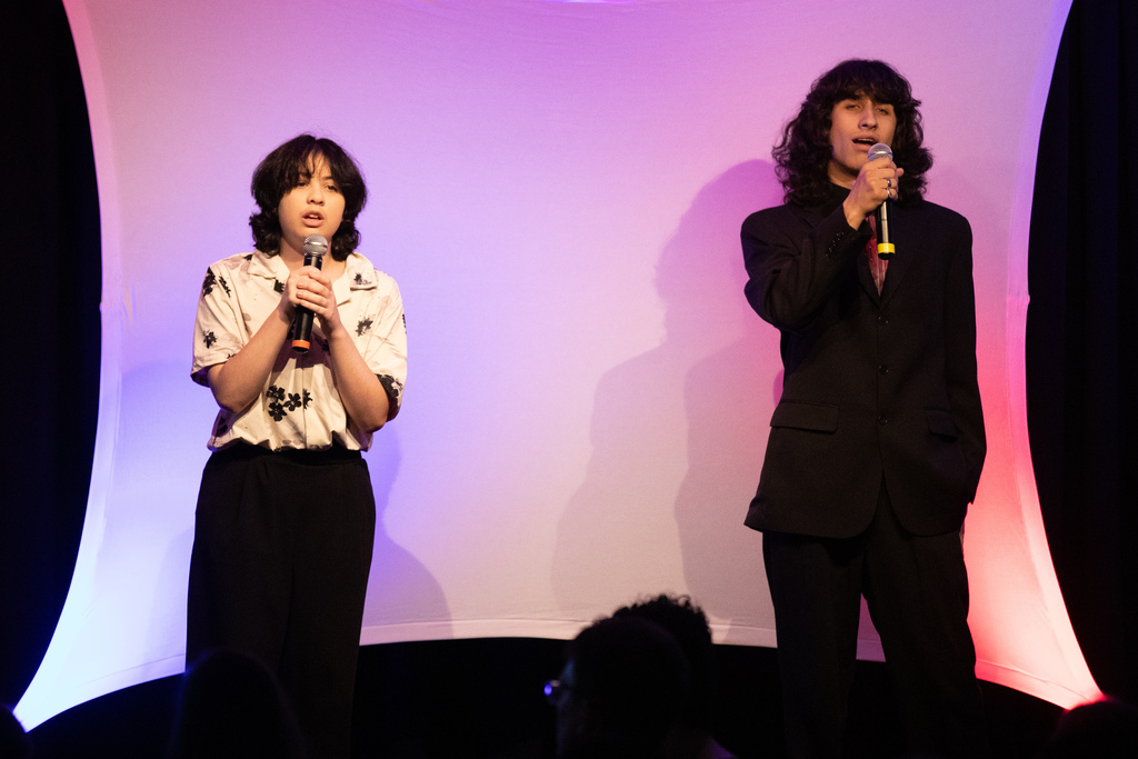 two students singing on stage