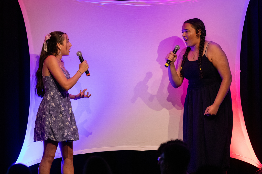 two students singing on stage