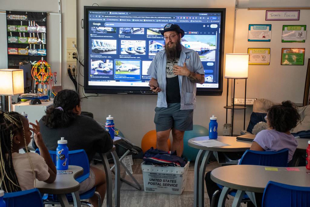 postal worker speaks with students