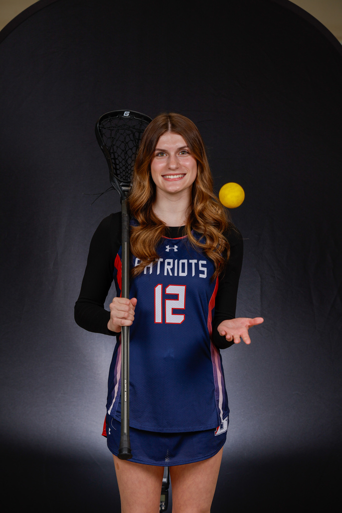 Alaina Donahue holding lacrosse stick on her shoulder and tossing yellow lacrosse ball in the air