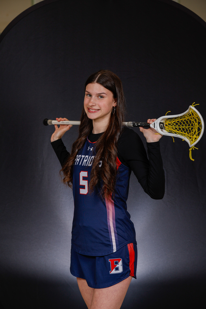 Kaitlyn Donahue holding lacrosse stick across  her shoulders
