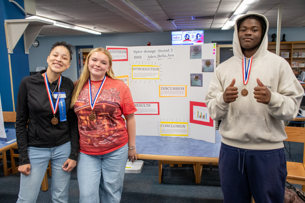 students pose for photo with their science fair project at BHS