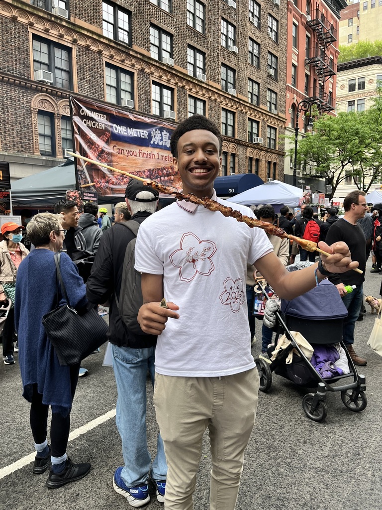 student from bhs asian cultural club poses with food skewer during trip to nyc
