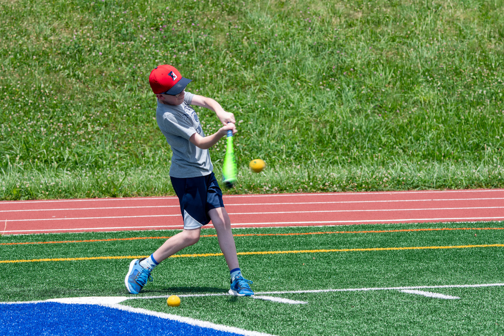 student hitting baseball