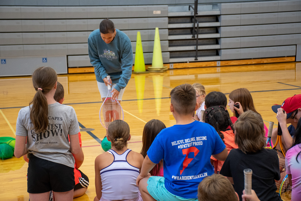 teacher demonstrates with tennis racket