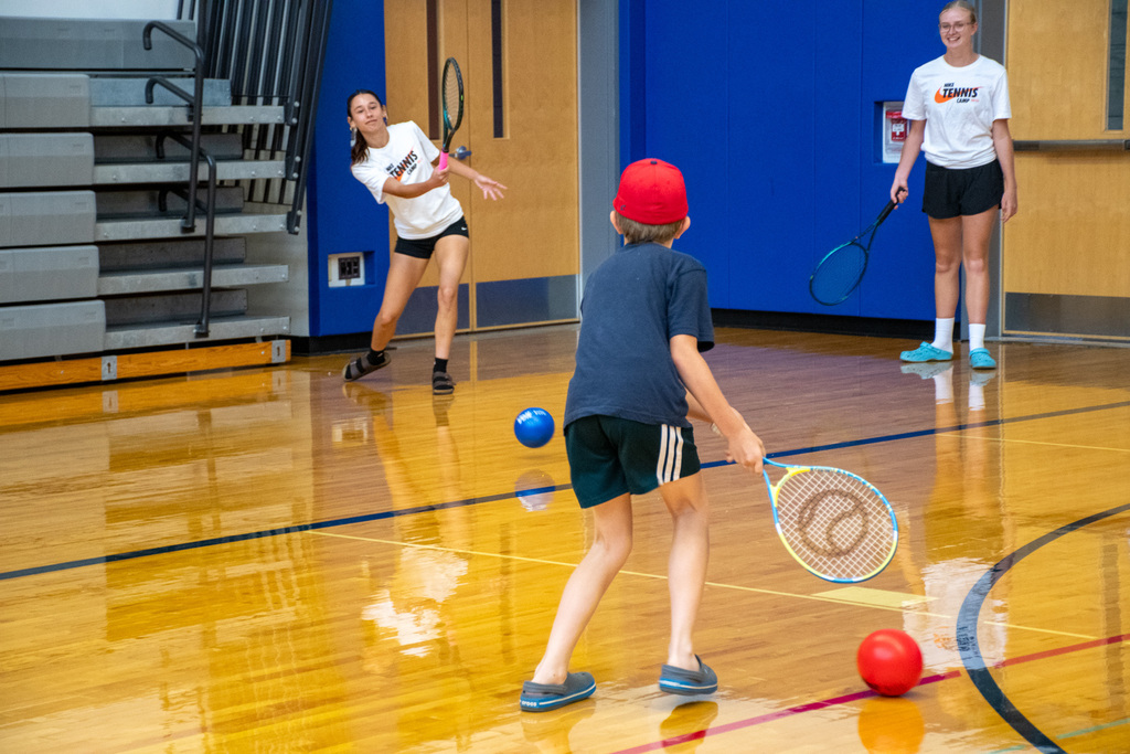 three students hitting ball to each other using tennis rackets