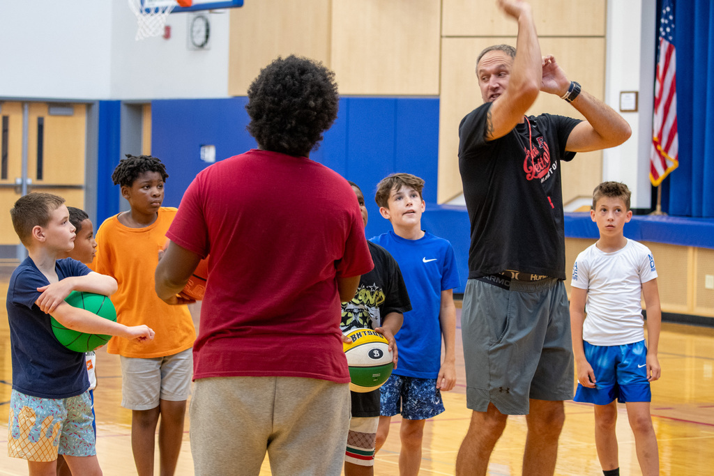 coach demonstrates shooting a free throw while students watch