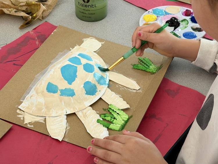 student paints sea turtle craft on paper plate 