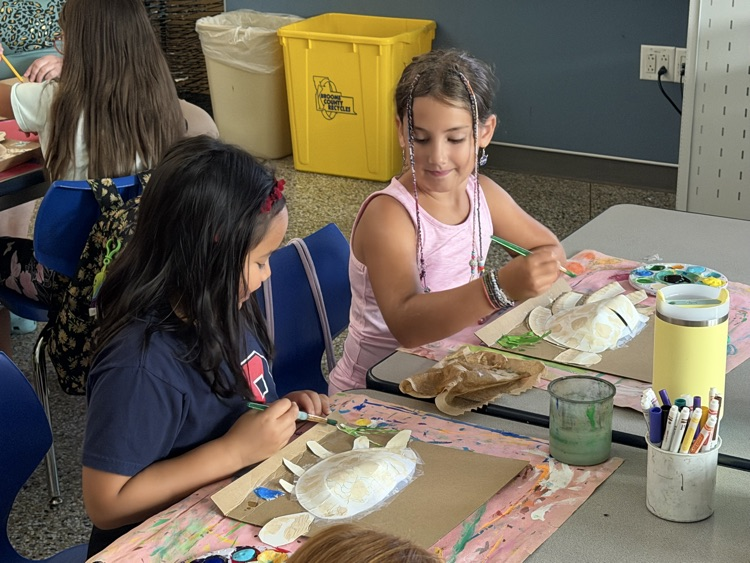 two students paint paper plates to look like sea turtles