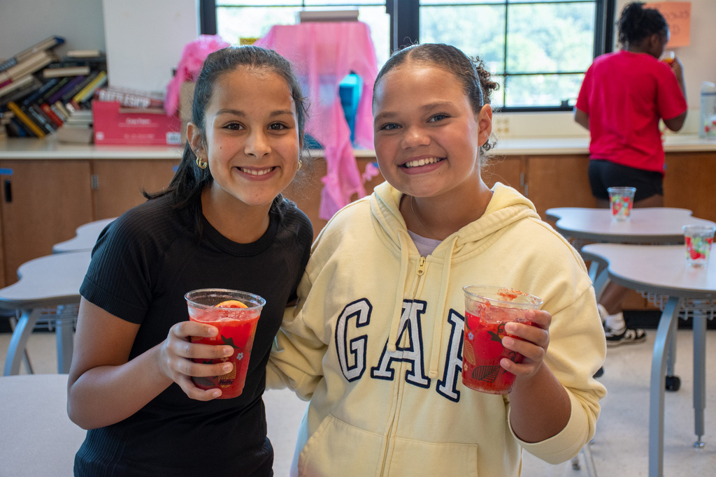 two students smile for camera holding cups of fresh squeezed strawberry lemonade