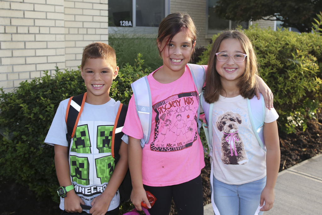 three students pose for photo in front of calvin coolidge elementary school