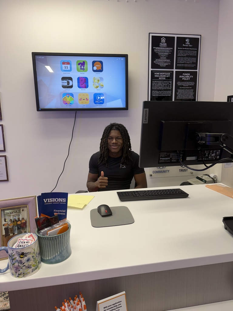 visions intern rasheen sitting at teller's desk giving thumbs up