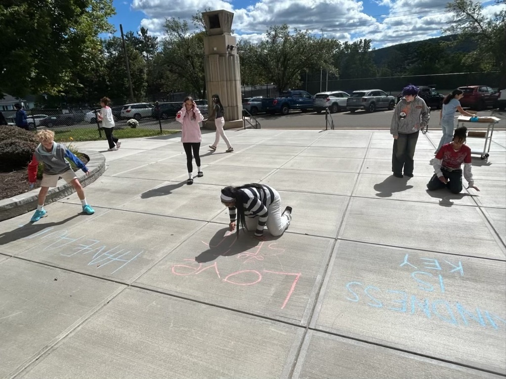 west middle students write positive messages with chalk outside of school