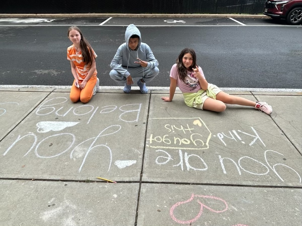 three east middle students pose for camera while writing with chalk