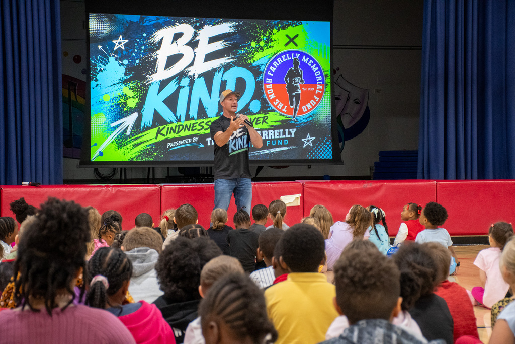 guest speaker talks to students in Calvin Coolidge gymnasium with image behind him that says "Be Kind"