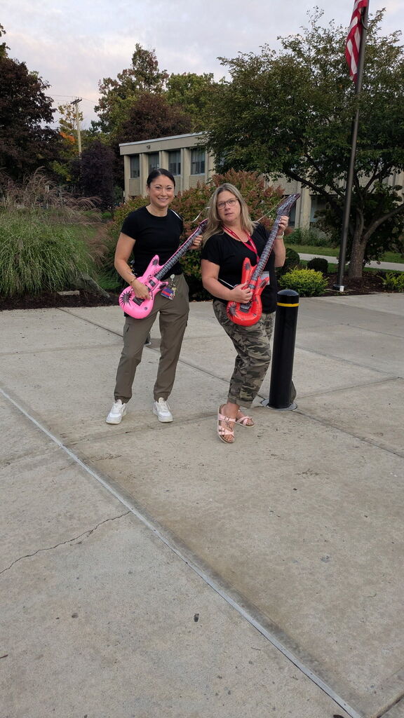 horace mann staff members pretend to play inflatable guitars outside of school
