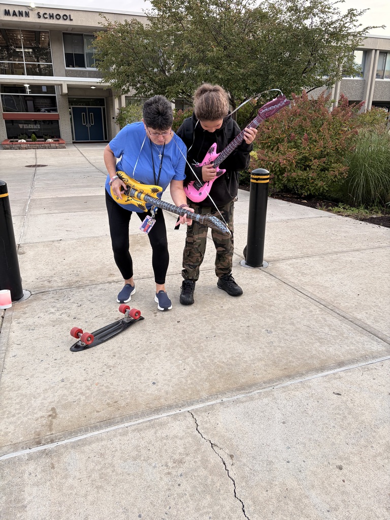 horace mann staff member pretends to play inflatable guitar with student outside of school