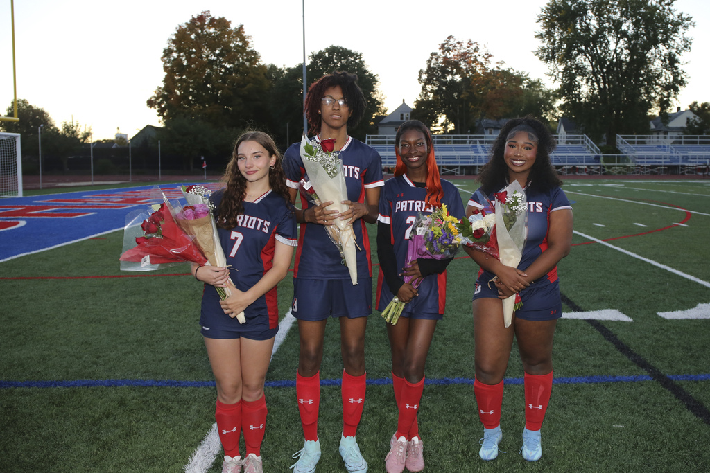 four seniors from BHS girls soccer team pose for photo holding flowers