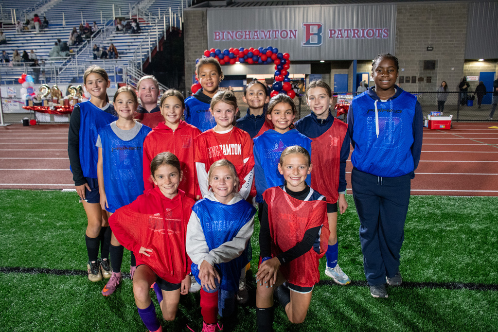 girls youth soccer players pose for photos on turf of alumni stadium