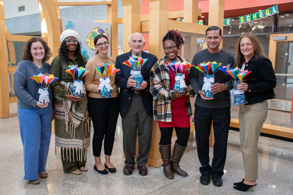 board of education members and superintendent dr. tonia thompson pose for photo holding arrangements of paper flowers inside macarthur elementary school