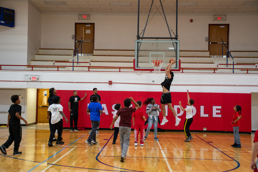 binghamton university men's basketball player dunks on hoop in east middle school gym