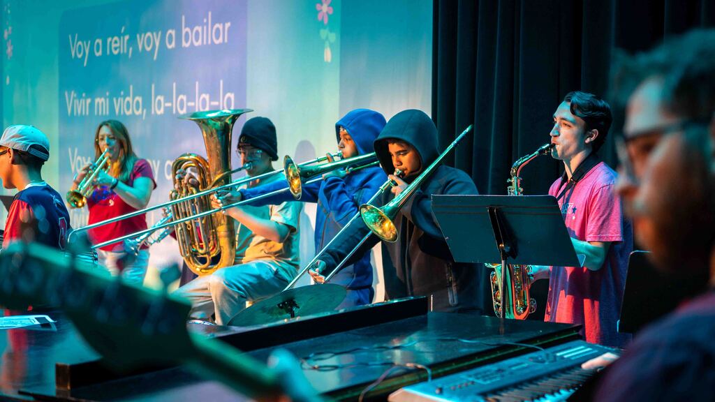 east middle students and teachers play band instruments on stage