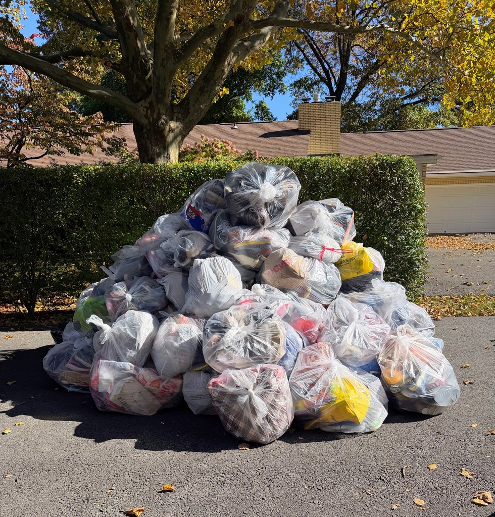 a pile of plastic bags filled with shoes sits on sidewalk