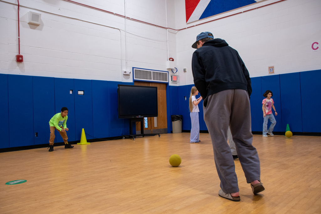 binghamton university lacrosse player gets ready to kick soccer ball to student inside horace mann gymnasium