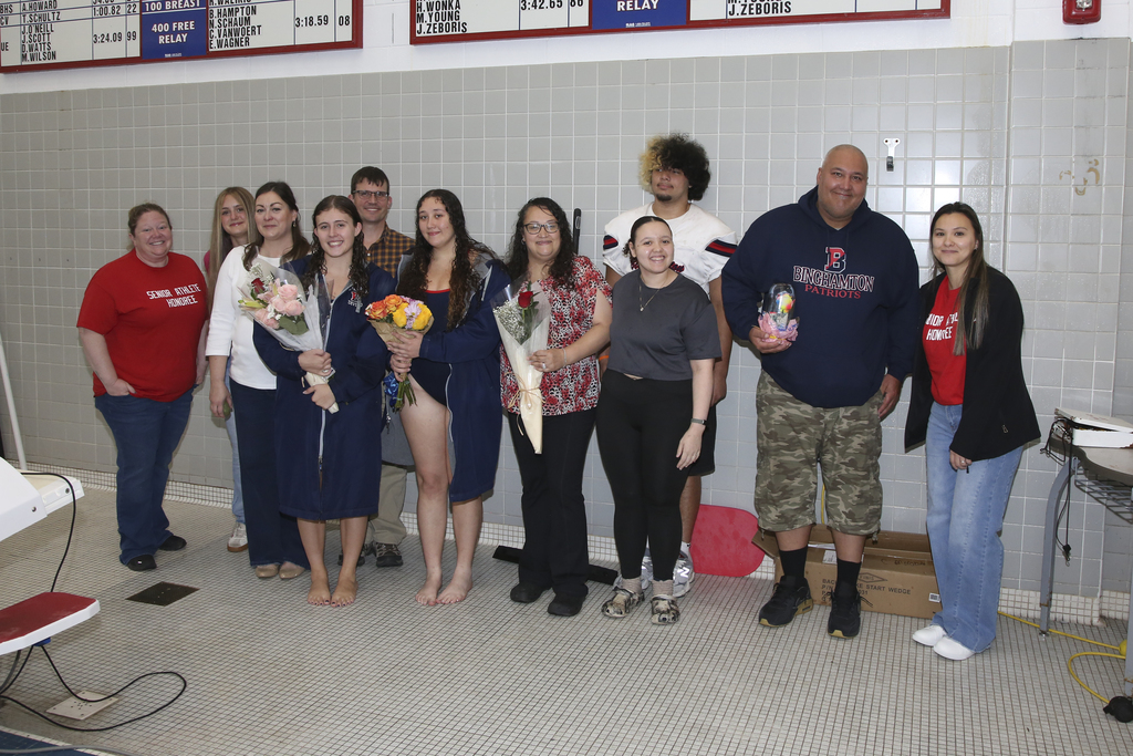seniors from girls swimming and diving team pose for photo with their family members and bhs staff