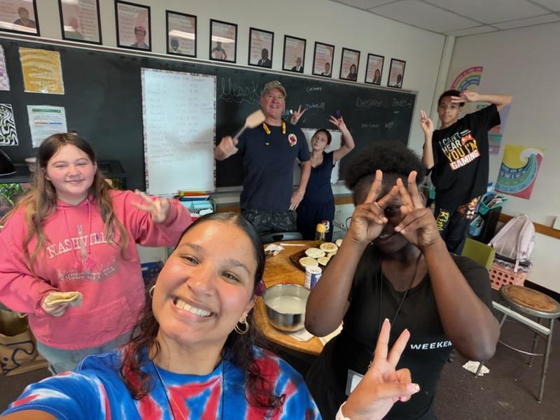 students and teacher take selfie with luis from happy pappy restaurant who holds up a spatula