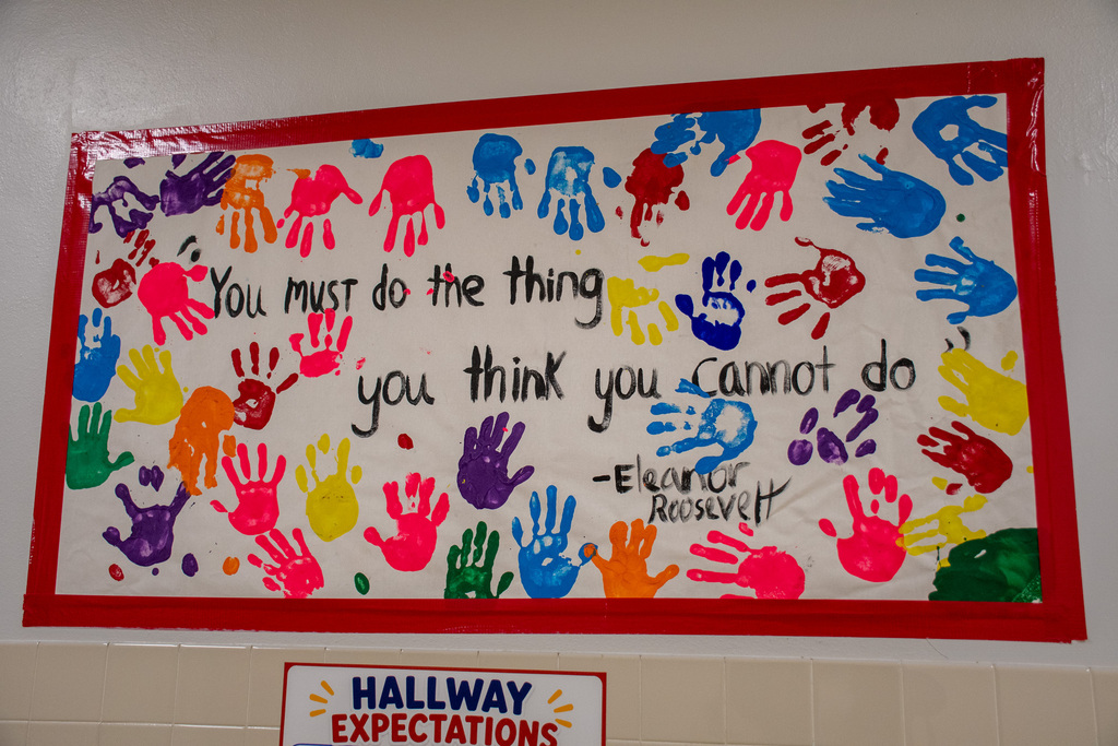poster in hallway with children's handprints and a quote from Eleanor Roosevelt that says "you must do the thing you think you cannot do"