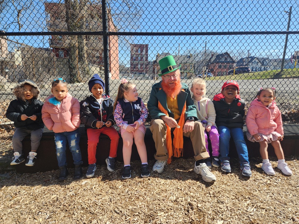 pre-k students and man dressed as leprechaun sit outside