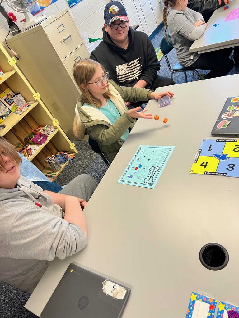 Student rolls dice in math game.