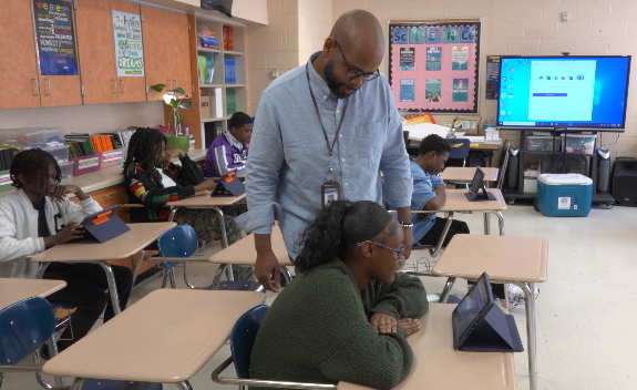 Principal Brandon Key helps a scholar at Wilkerson Middle School 