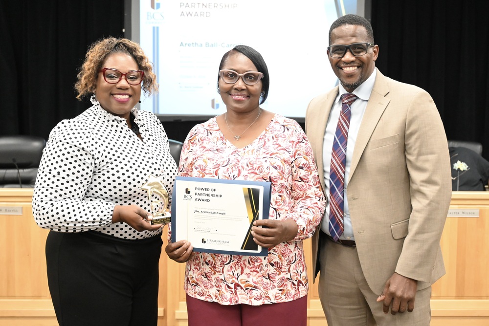 Mrs. Aretha Ball-Cargill (center) receives the Power of Partnership Award from Family Engagement Program Specialist Dr. LaKesha Douglas (left) and Board President Sherman Collins (right)