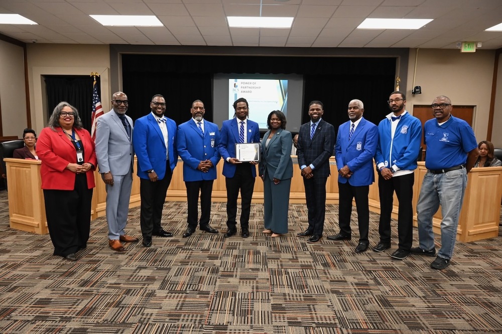 Adrianne Marbury, Dr. Mark Sullivan, members of Tau Sigma Chapter of Phi Beta Sigma Fraternity, Inc. (in blue), Principal  Tronci Southall-Mason (center)