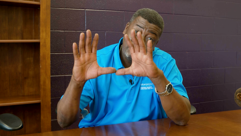 Daniel Gales, head custodian at A.H. Parker High Schools, does the U salute.