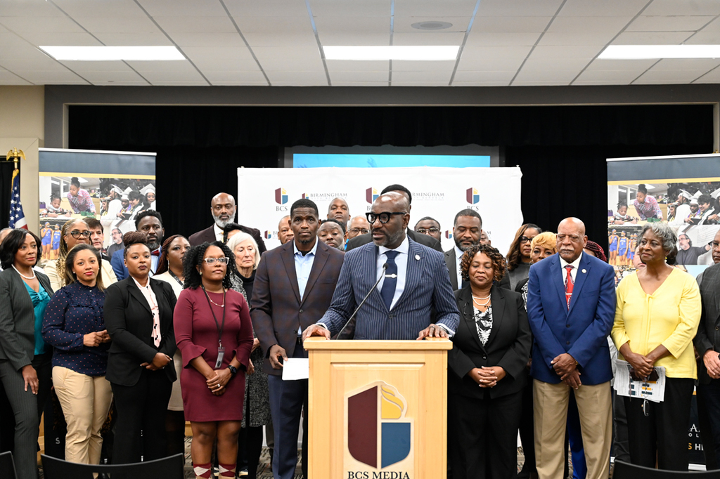 Superintendent Dr. Mark Sullivan speaks to the media surrounded by board members, community leaders, administrators, faculty and staff.