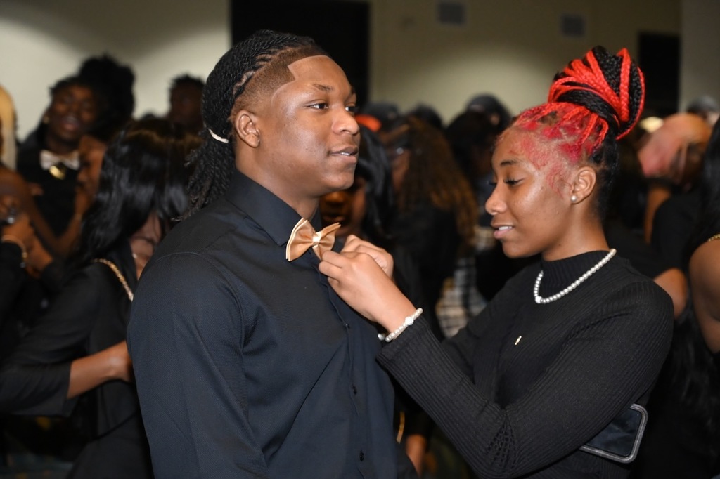 Scholars helped each other with their pins. 