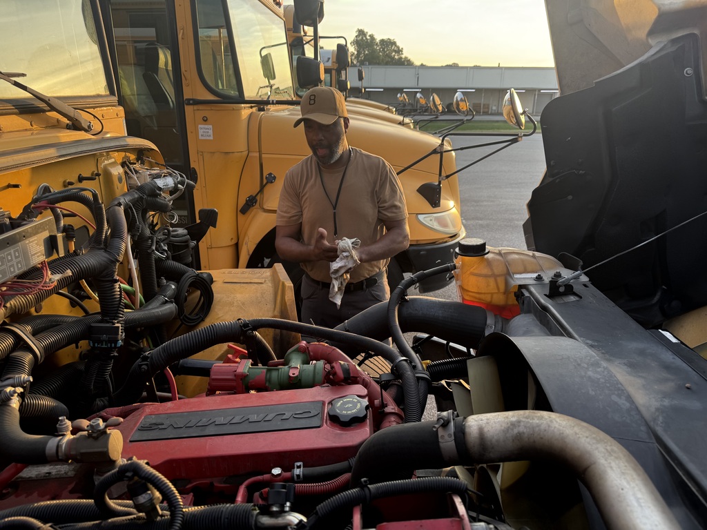 Mr. Walker works on a bus engine