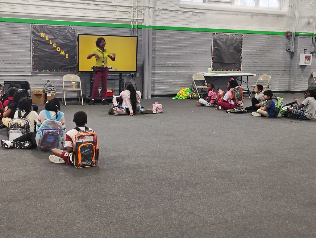 3rd grade students sitting on the gym floor being instructed by Principal Lawson