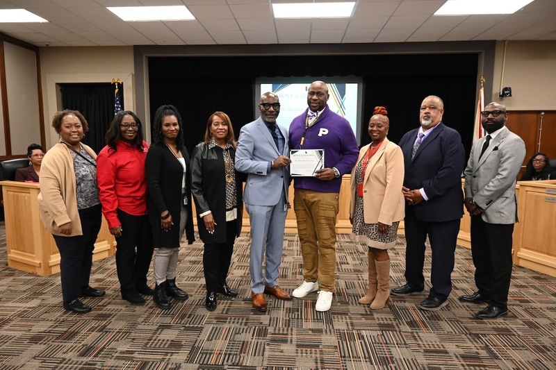 Dr. Mark Sullivan, Wendale Pierson (middle, holding certificate), Parker Principal Darrell Hudson (second from right) and Board Member James Sullivan (far left) with well-wishers from the Parker family